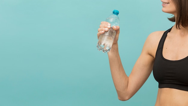 Garrafa de fitness cheia de água e mulher em forma