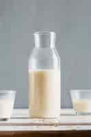 Foto grátis garrafa de leite com copos na mesa