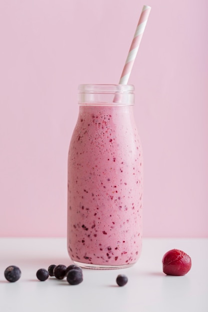 Garrafa de smoothie rosa vista frontal com palha e frutas