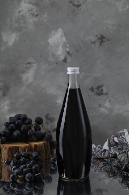 Foto grátis garrafa de vinho com uvas na peça de madeira