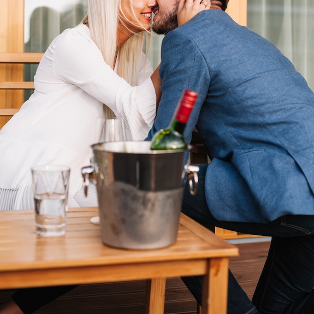 Foto grátis garrafa de vinho dentro do balde de gelo na frente do casal romântico amando juntos