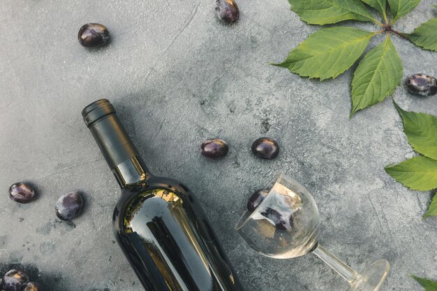 Garrafa de vinho tinto verde videira copo de vinho e uva madura no fundo da mesa de pedra escura vintage vi ...