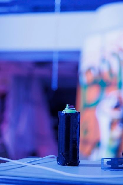 Foto grátis garrafas de aerossóis usadas para graffiti em paredes negligenciadas, latas de tinta spray em armazém deserto com luzes brilhantes roxas. edifício vazio danificado com luzes fluorescentes de néon. fechar-se.