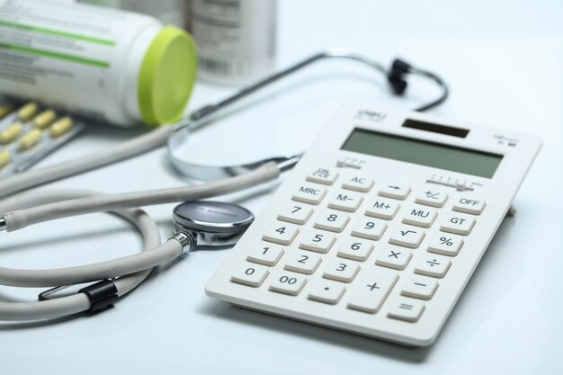 Garrafas de calculadora, estetoscópio e remédios no fundo branco