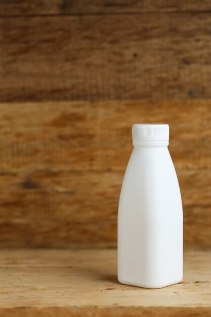 Garrafas de leite em plástico branco no fundo retro da mesa de madeira