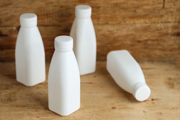 Foto grátis garrafas de leite em plástico branco no fundo retro da mesa de madeira