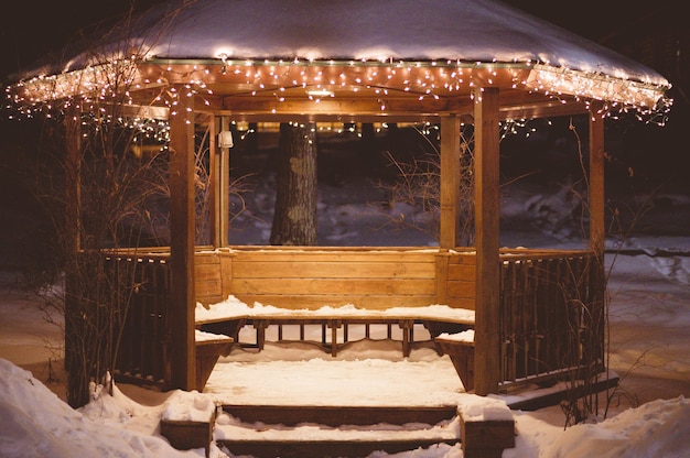 Gazebo de madeira com neve em seu telhado no inverno