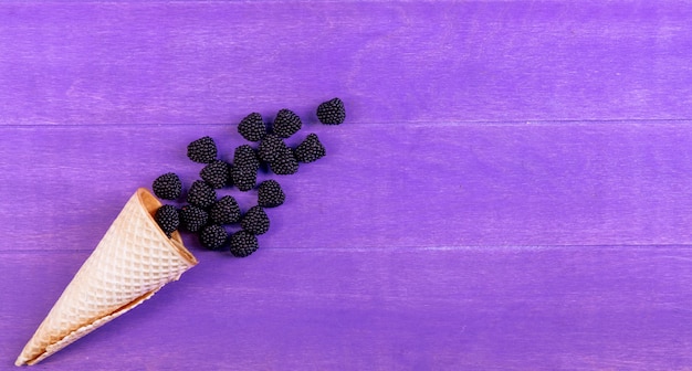 Foto grátis geléia de vista superior sob a forma de uma amora com um cone de waffle em um fundo roxo