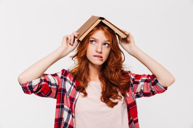 Gengibre mulher de camisa, segurando o livro na cabeça como telhado