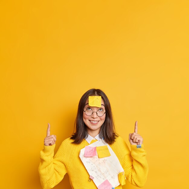 Gerente feminina de sucesso positivo em um suéter casual com papéis e adesivos presos por sorrisos de clipes de papel e pontos no espaço da cópia