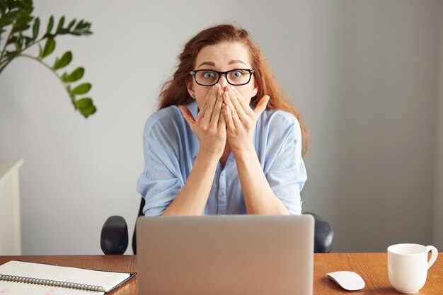 Gerente feminina sentada à mesa do escritório, olhando com expressão de surpresa