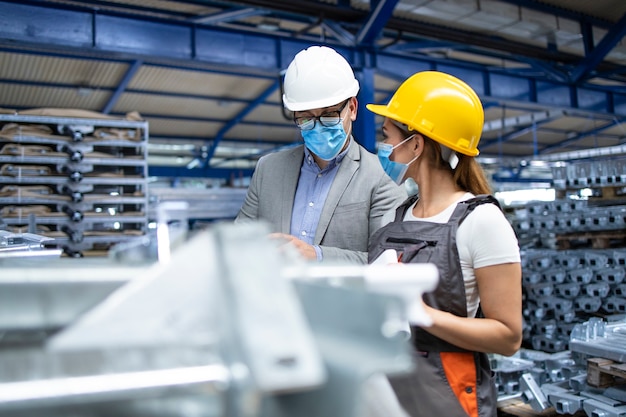 Gerente supervisor industrial com máscara higiênica falando com o trabalhador na fábrica de produção