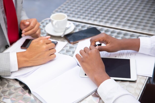 Gerentes sentados à mesa com documentos e dispositivos digitais