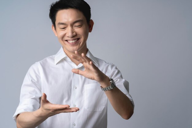 gesto de mão masculino asiático atraente presente mostrar espaço de cópia para suas ideiasfelicidade sorriso positivo espaço de controle de ponto de mão masculino asiático no ar fundo branco