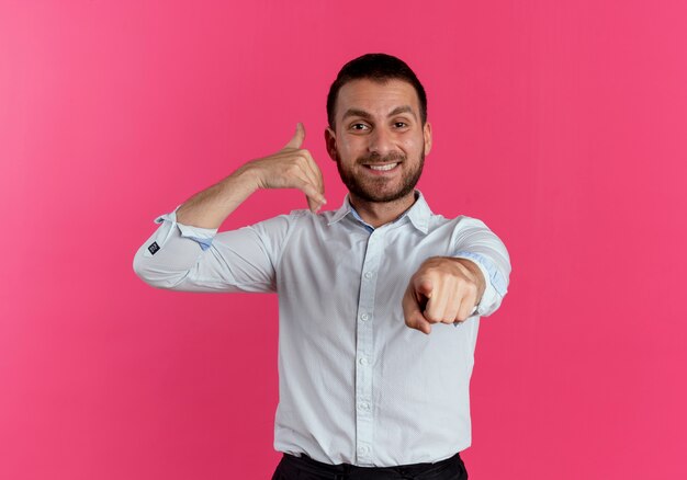 Gestos sorridentes de homem bonito me chamam sinal de mão apontando isolado na parede rosa