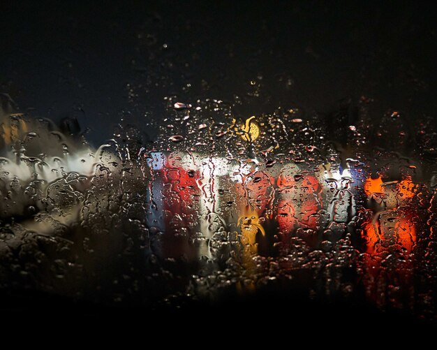 Gotas de água na janela borrando as luzes do lado de fora com um preto