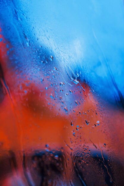 Gotas de água no fundo de vidro de néon. Cores vermelho e azul