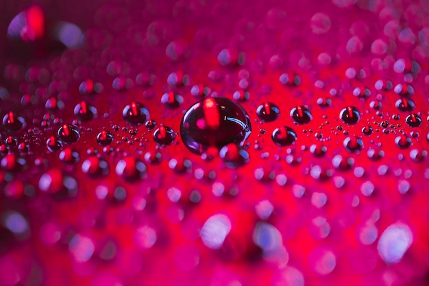 Gotas de água transparente texturizadas na superfície vermelha escura