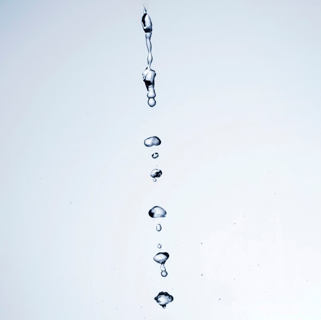 Gotas de líquido transparente sobre fundo branco, com espaço de cópia