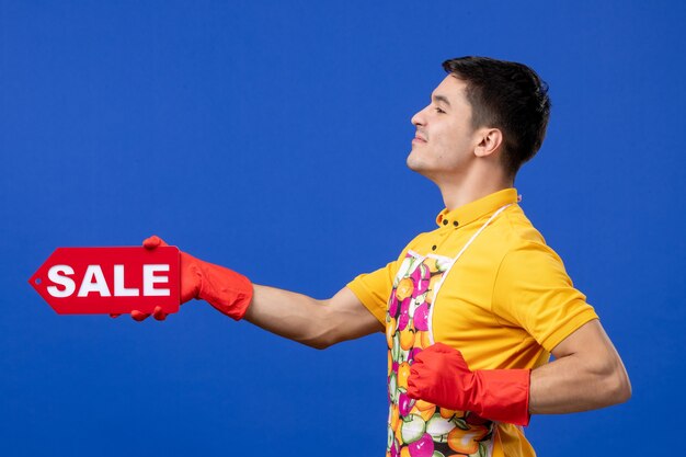 Governanta masculina confiante de frente para uma camiseta amarela segurando uma placa de venda no espaço azul