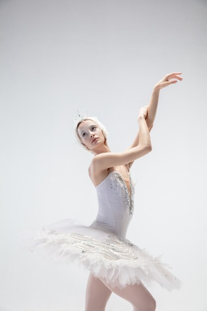 Graciosa bailarina clássica dançando isolada no fundo branco.