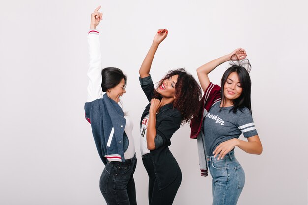 Graciosa modelo feminina negra dançando entre amigos latinos e asiáticos e cantando a música favorita. Foto interna de estudantes internacionais se divertindo depois de fazer compras juntos.