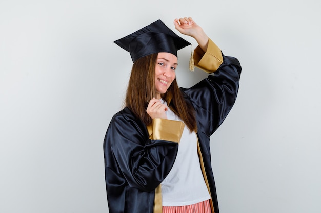 Foto grátis graduada feminina mostrando gesto de vencedor em roupas casuais, uniformes e parecendo feliz. vista frontal.