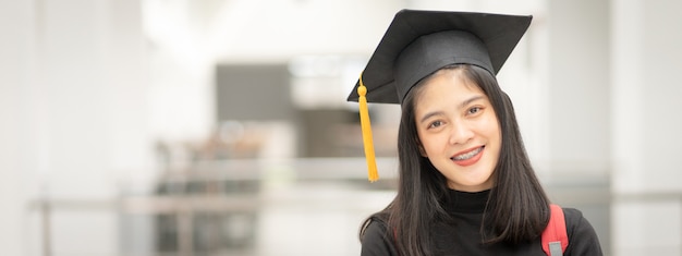 Graduado universitário jovem feliz mulher asiática em vestido de formatura e boné no campus da faculdade. foto de estoque de educação