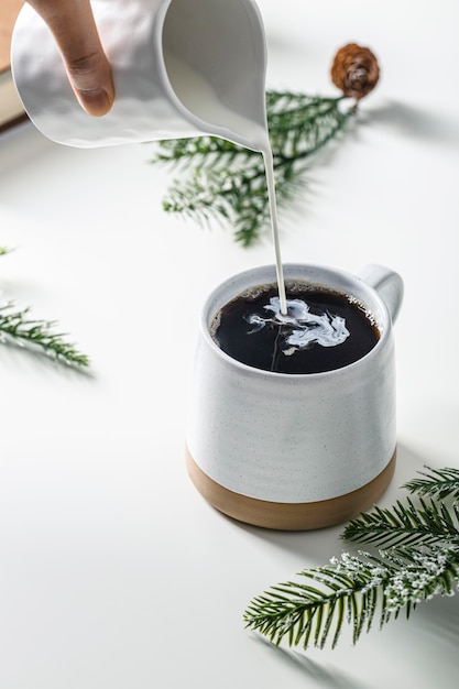 Foto grátis grande ângulo da mão servindo creme na caneca de café