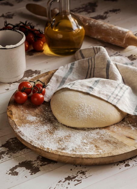 Foto grátis grande ângulo de massa de pizza coberto com pano e tomate