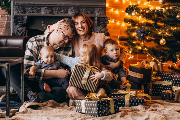 Grande família na véspera de Natal com presentes pela árvore de Natal