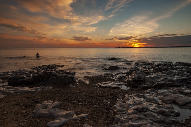 Grande plano de nadadores na Gales do Sul durante o pôr do sol