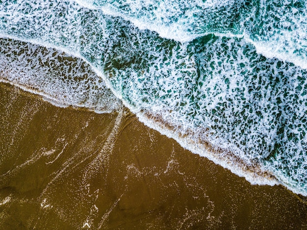 Grande plano de ondas do mar azul em uma praia arenosa