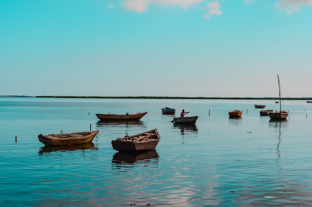 Foto grátis grande plano de pequenos barcos de madeira na água com uma pessoa afro-americana em um deles