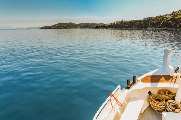 Grande plano de uma canoa branca no corpo de água perto de uma ilha verde sob um céu azul claro