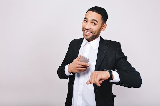 Grande sucesso, bons resultados na carreira de jovem bonito em camisa branca, jaqueta preta sorrindo com telefone. Empresário elegante, sorrindo.