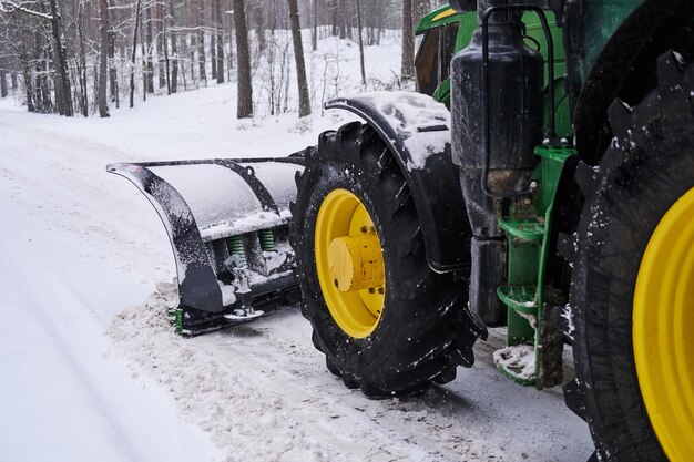 Grande trator especial está removendo a neve da estrada florestal.