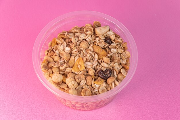 Granola em tigela de plástico na superfície rosa