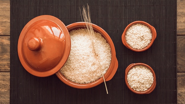 Foto grátis grãos de arroz branco cru no pote e duas taças no placemat