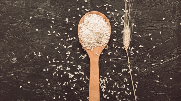 Grãos de arroz branco na colher de pau, sobre fundo cinzento áspero