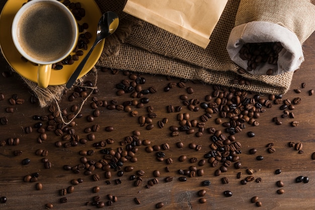 Grãos de café colocados na mesa com saco e copo