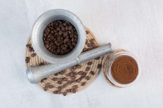 Grãos de café em almofariz e pilão com cacau em pó