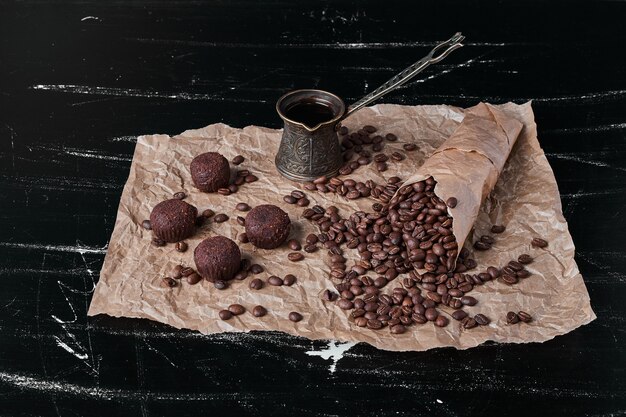 Grãos de café em fundo preto com bombons de chocolate.