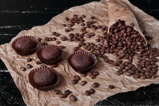 Grãos de café em fundo preto com bombons de chocolate.