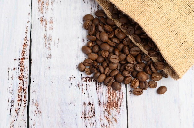 Foto grátis grãos de café em sacos de cânhamo em uma mesa de madeira branca.