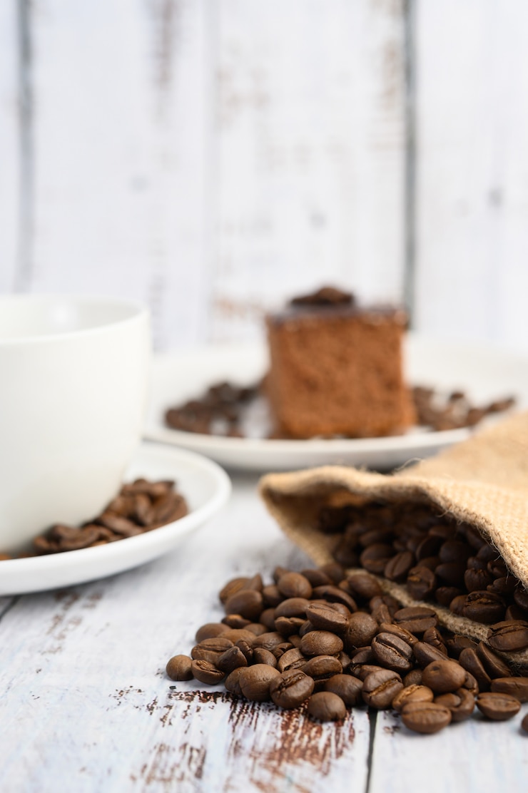 Foto grátis grãos de café em sacos de cânhamo em uma mesa de madeira branca.