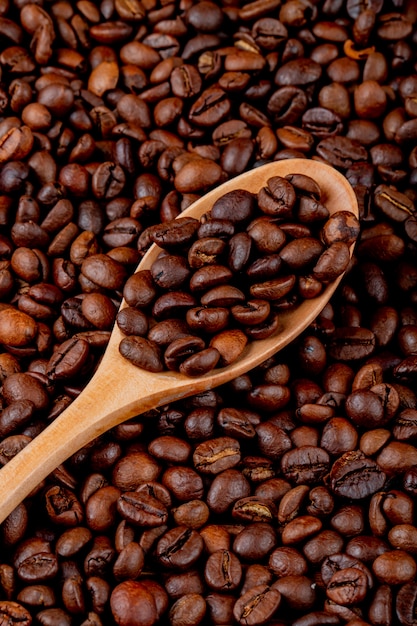Grãos de café em uma colher de pau na vista superior de grãos de café
