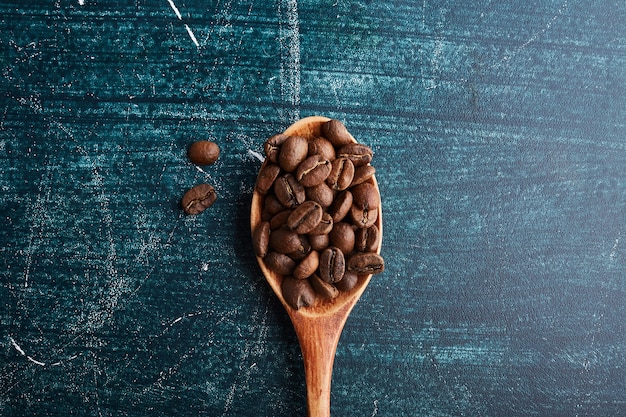 Grãos de café em uma colher de pau.