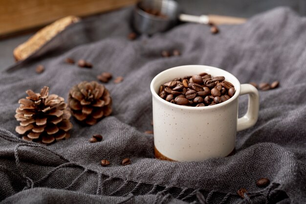 Grãos de café em uma xícara branca em um lenço cinza