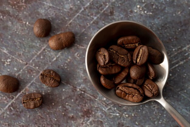 Grãos de café na colher com fundo de mármore